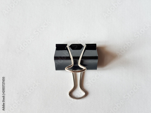 Minimalist black binder clip rests on clean white surface