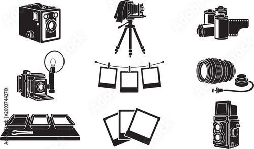 A collection of black and white featuring vintage equipment, including box cameras, bellows cameras on tripods, rolls, frames on a string, lenses, and darkroom trays