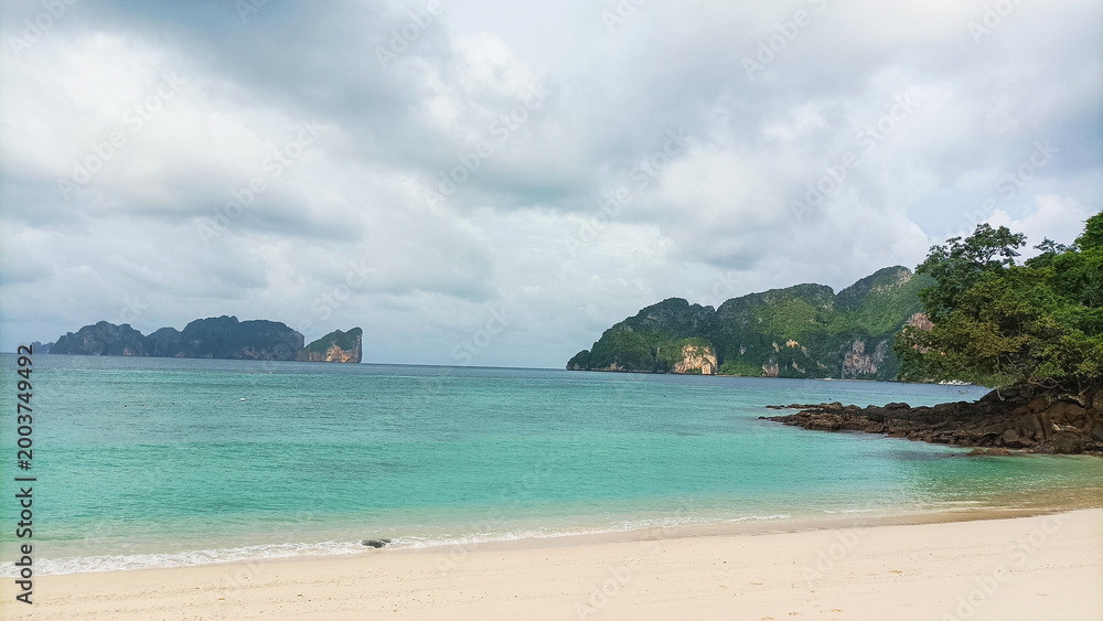Obraz premium Phi Phi Island on August 15, 2025: Tropical beach shoreline with turquoise ocean and rocky cliffs