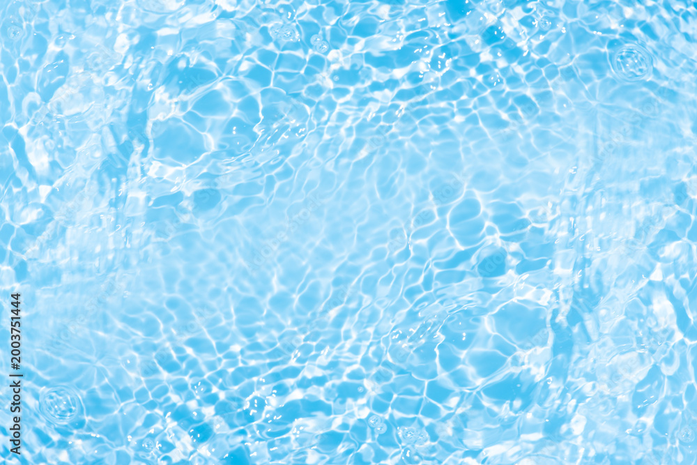 Obraz premium Blue water with ripples on the surface. Defocus blurred transparent blue colored clear calm water surface texture with splashes and bubbles. Water waves with shining pattern texture background.