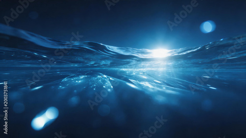 A serene underwater view showing sunlight beams filtering through calm deep blue ocean waves, with soft bokeh effects and sparkling light refracting through the water.