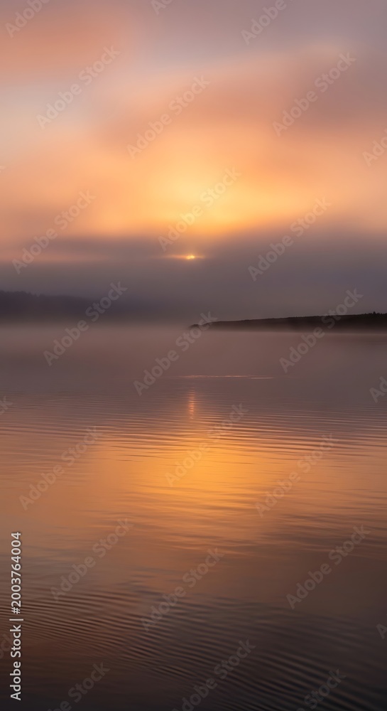 Fototapeta premium Stunning golden sunrise reflecting over a calm tranquil lake at dawn.