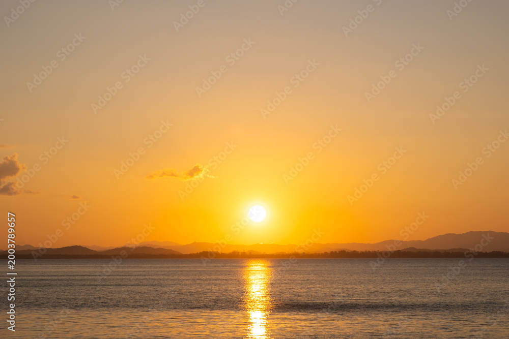 Obraz premium nature sky breathtaking golden sunset over a calm ocean, with the entire sky and water bathed in brilliant shades of yellow and orange. Streaky clouds enhance the dramatic display 