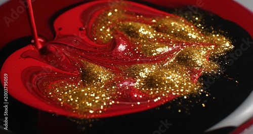 Vivid red and gold paint swirling together in a bowl, creating an artistic blend