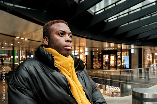 Young black man relaxing in urban shopping mall
