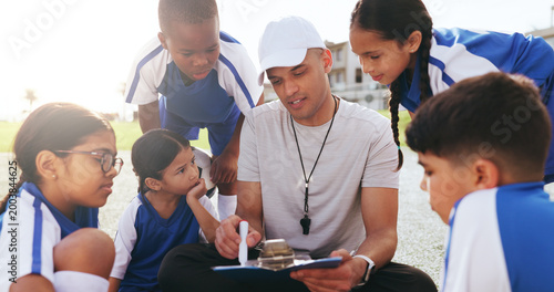 Man, coach and clipboard with children for soccer schedule, formation planning and training session. Person, checklist or kids for fitness attendance, coaching strategy and tactics for football match