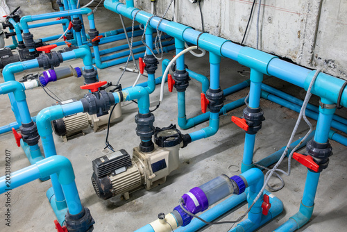 Quadro su tela Pool water pump system with multiple blue PVC pipes, ball valves, electric motor
