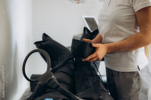 Bild auf Leinwand Technician preparing pressotherapy treatment for patient legs