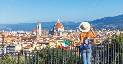Tableau sur toile Authentic female backpacker with straw hat holding Italy flag admiring the panor