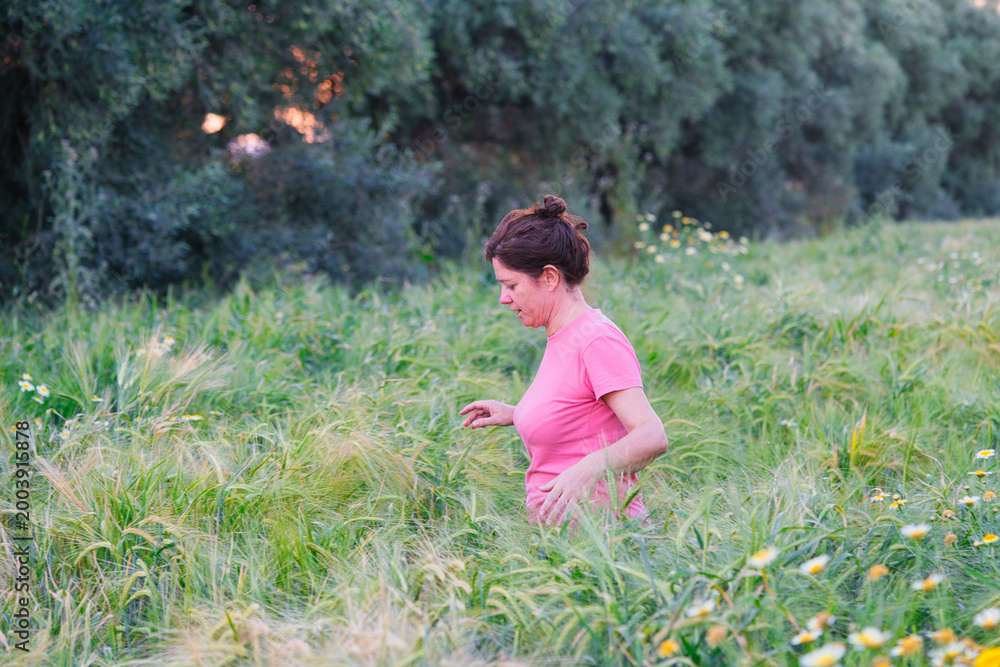 Fototapeta premium woman among ears of wheat in the field