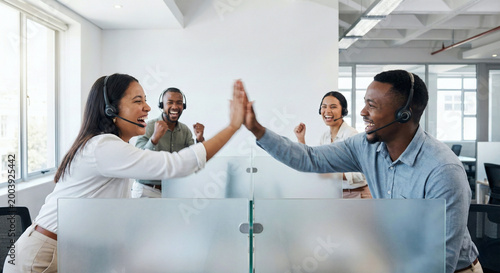Two smiling Black colleagues in a call center give each other a high five, celebrating success