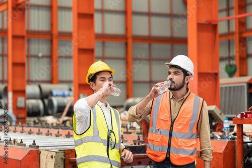 Technicians and supervisors are drinking water to cool off from the heat of working in the factory during the summer.