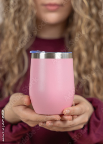 Blank pink 12 oz wine tumbler mockup in hands of young woman in red sweatshirt, copy space