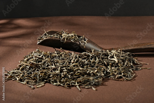 Fotografija Wooden tea scoop holding loose-leaf white tea in a close-up still life photograp
