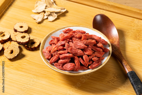 Fotografie Premium dried goji berries in a small ceramic bowl on a wooden tray with sliced