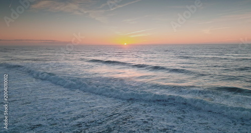 Foto Amazing sunset over the Atlantic Ocean creates pastel colors across the bright sky and reflects on rolling ocean waves