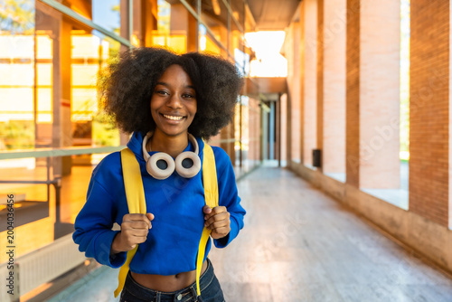Happy black student standing on university campus path