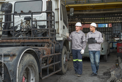 Fotografie Caucasian and Middle Eastern mid-adult male technicians walk through an Asian co