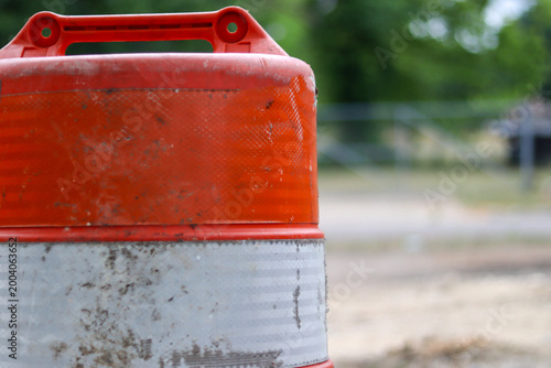 Close-up of orange construction traffic barrel with reflective stripes and copy space