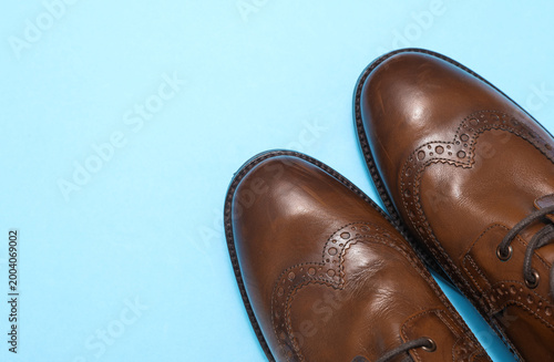 Fotografie Brown leather classic men's boots on a blue background. Top view