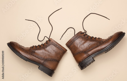 Fotografie Brown leather classic men's boots on a beige background. Top view
