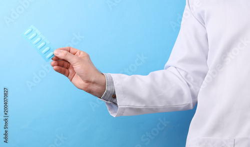 Foto Doctor in a white medical coat holding rectal suppositories on a blue background