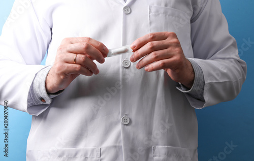 Cuadro en lienzo Doctor in a white medical coat holding rectal suppositories on a blue background