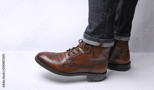 Quadro su tela Male legs in jeans and classic leather brogue boots on a white background