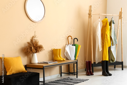 Konstfotografi Interior of room with bench, gumboots, umbrellas and different colorful raincoat