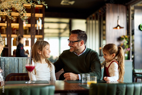 Father Laughing With Two Daughters During Casual Family Brunch At Modern Restaurant