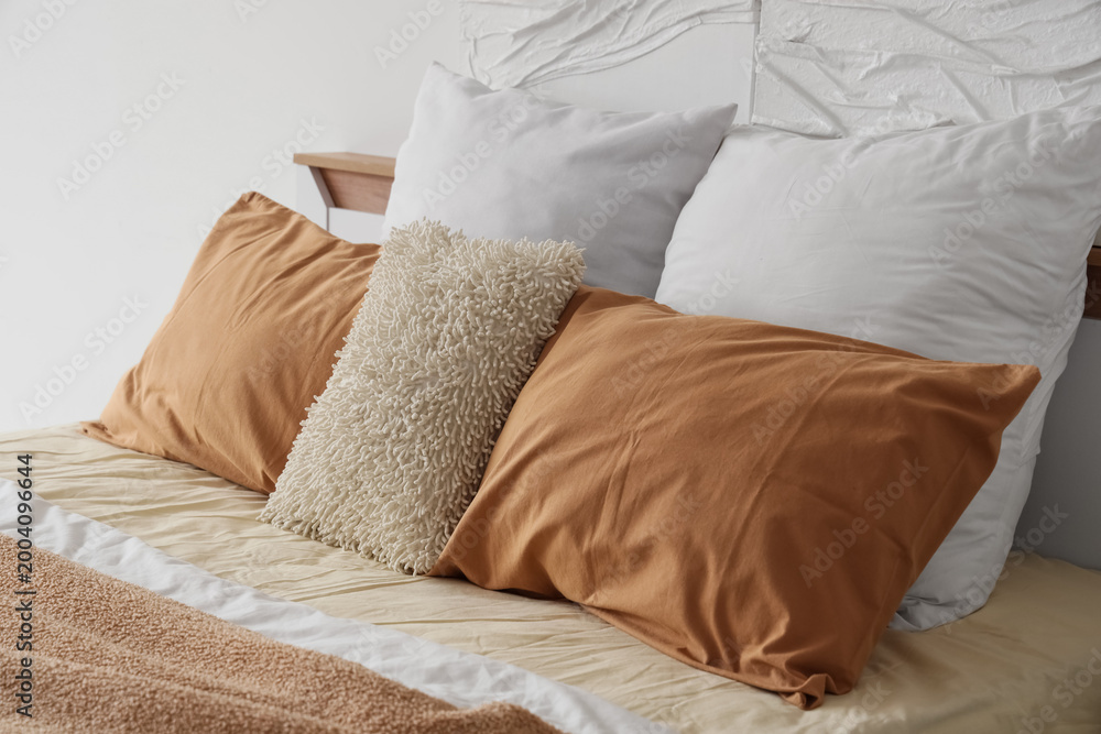 Obraz premium Cozy bed with soft pillows in stylish bedroom, closeup