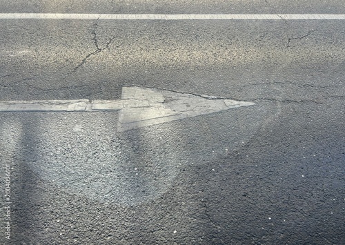 Urban surface and infrastructure texture. White arrow on asphalt road indicating direction for cars.