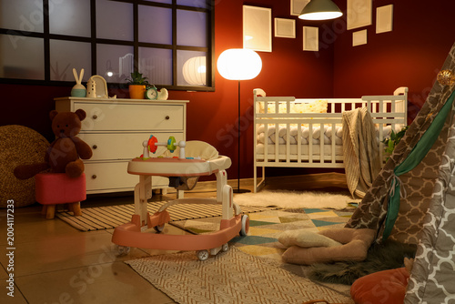 Interior of stylish children's bedroom with tent, baby walker and toys at eve...