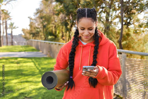 Quadro su tela front view of Young latina woman checking phone before outdoor yoga session