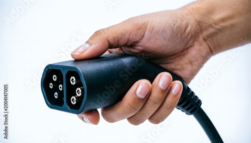 Close-up of a hand holding a universal EV charging connector isolated on a pure white background.