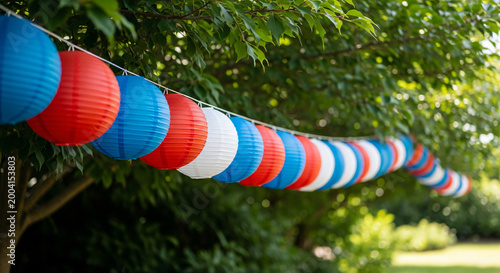 Red white and blue paper lanterns hanging from a garden tree