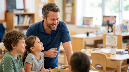 Smiling male teacher interacting with elementary school children in bright classroom early childhood education and primary school learning concept