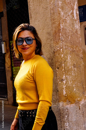 фотографія Smiling woman posing against urban wall wearing sunglasses
