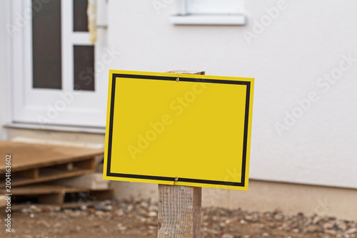 Obraz na płótnie Construction site with a blank yellow sign near a building entrance during dayli