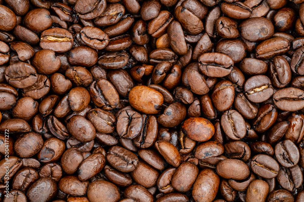Fototapeta premium Coffee beans spread out on a surface showing different shapes and colors in natural light in a simple setting