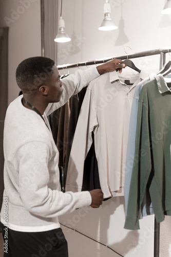Canvastavla Customer selecting shirt from rack while browsing new arrivals in modern fashion