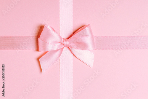 Pink satin ribbon bow centered on pink background close-up