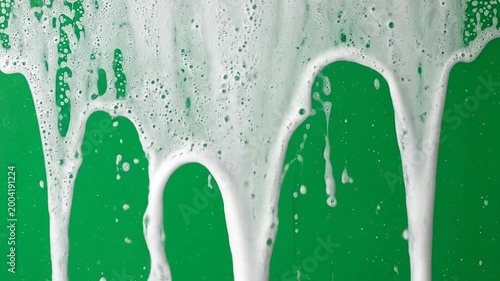 Bubbles and foam cascade down a vibrant green background