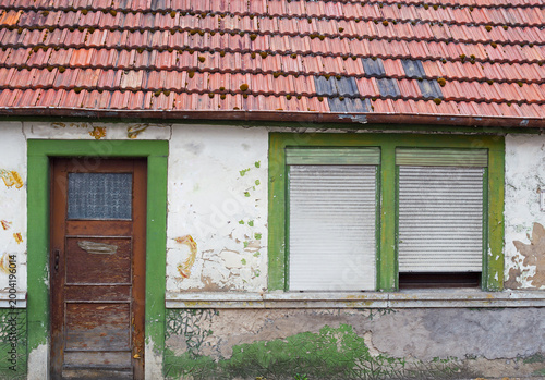 Foto Old house with peeling paint and rusted roof in a quiet area on a sunny day
