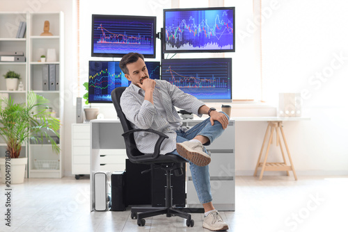 Thoughtful male trader sitt...