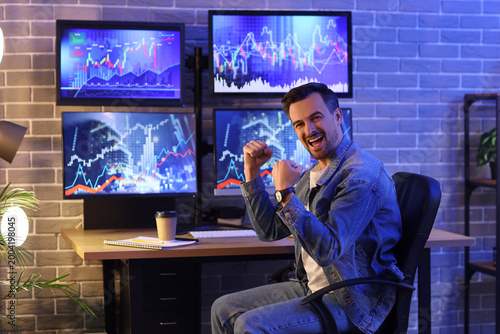 Happy male trader sitting i...