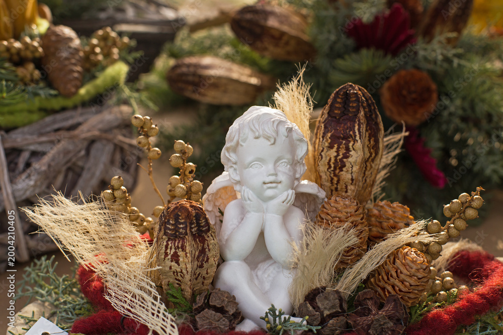 Naklejka premium Winter decoration features a white angel figure among natural elements and colorful accents in a festive setting