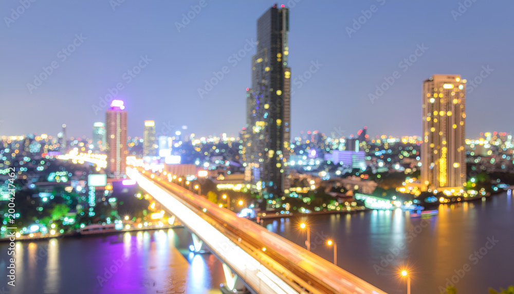 Naklejka premium Illuminated river bridge and modern skyline at night.