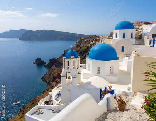 Whitewashed Santorini clifftop village with blue domed churches above the Aegean Sea.