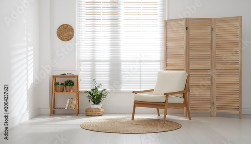Minimal Scandinavian living room with wooden chair and divider.